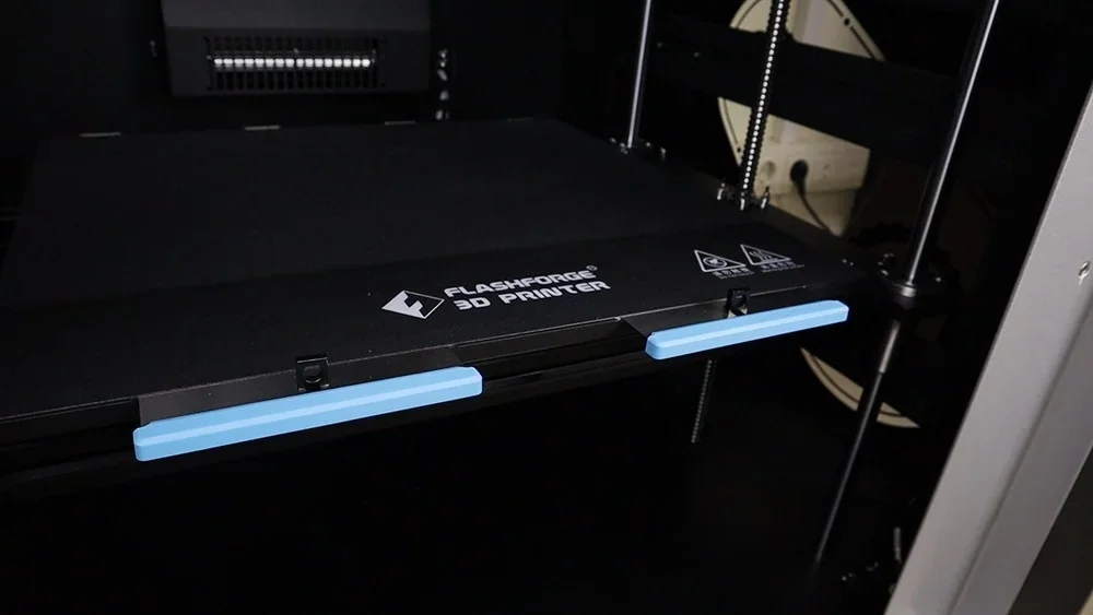 Flashforge Creator 4 3D printer interior showing the build platform with blue handles, machine branding visible.