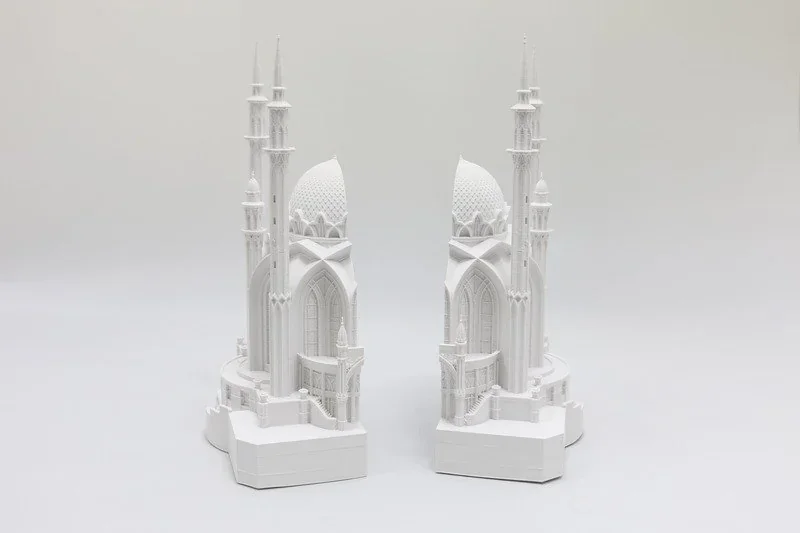 Two intricate white architectural models, showcasing detailed spires and arches, 3D printed by Flashforge Creator 4 against a plain background.