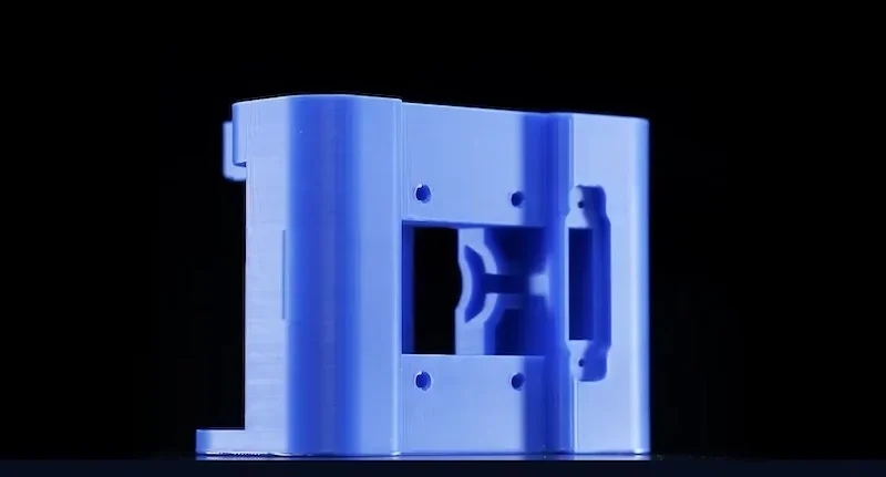 Blue 3D-printed component made by Flashforge Guider 3 Ultra on a black background, showcasing precise geometric design and multiple screw holes.