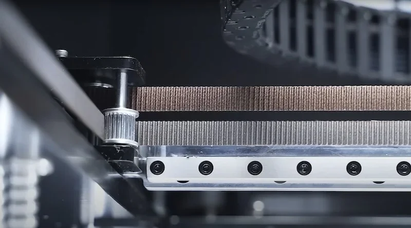 Flashforge Guider 3 Ultra detail showing precision belt and gear mechanism, highlighting advanced engineering components in a sleek, industrial design.