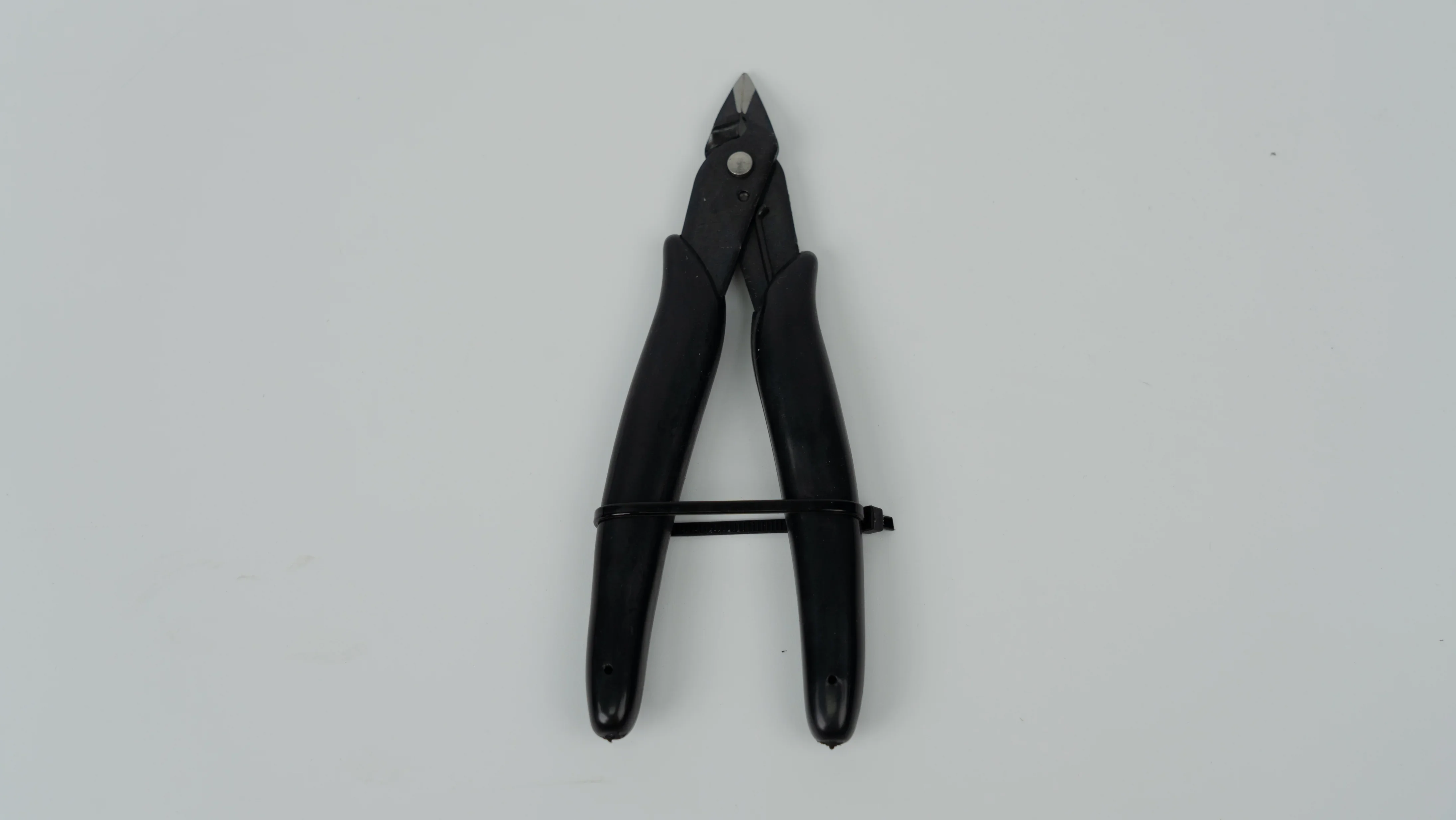 Wire cutter with black handles, resting on a gray background.