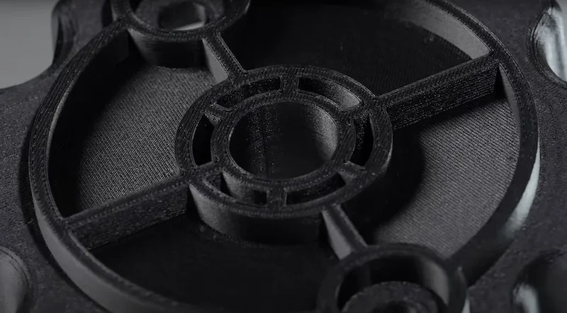 Close-up of a black 3D-printed mechanical part with circular design, printed by the Flashforge Guider 3 Ultra, showing intricate details and precision.