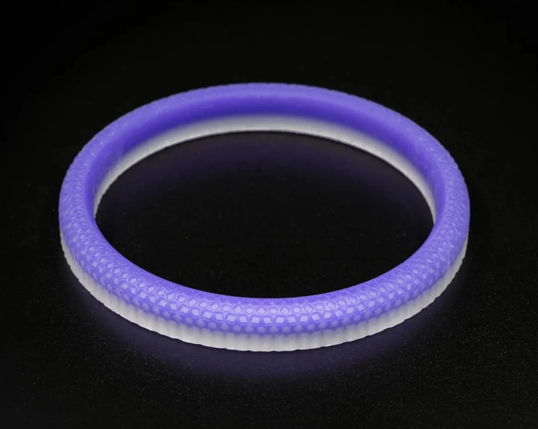 Purple circular 3D-printed object with textured surface, created by Flashforge WaxJet 400, on a black background.