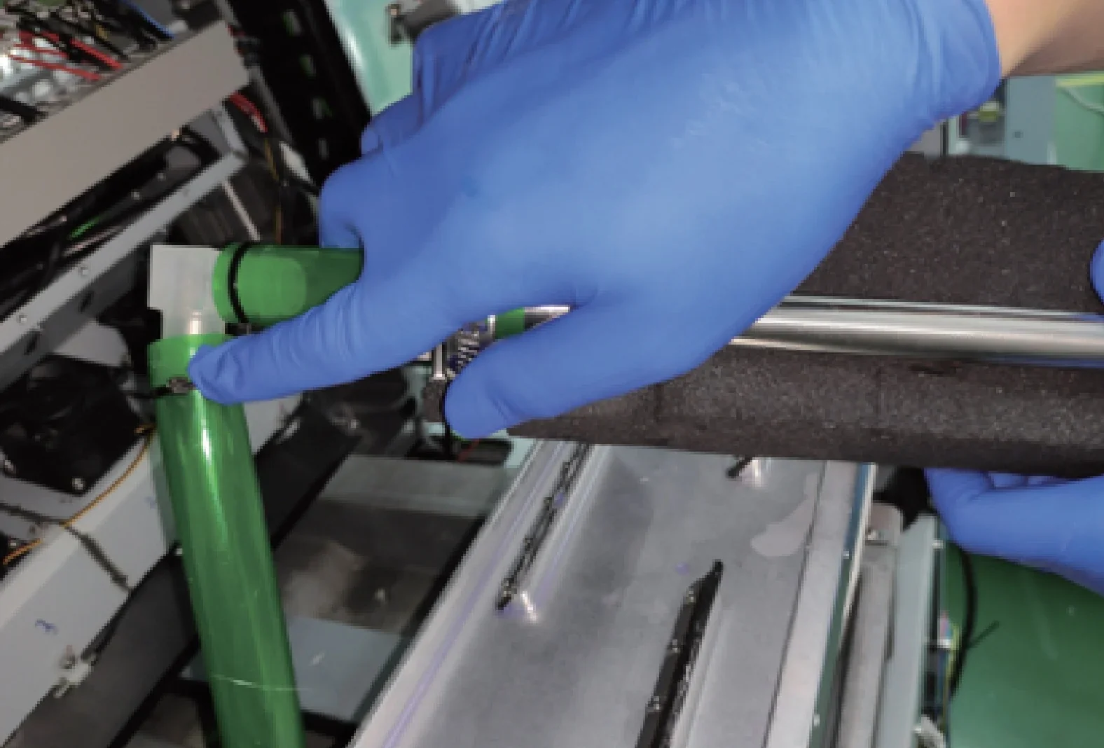 Blue-gloved hands work on Flashforge WaxJet 400 3D printer parts inside a machine, featuring a green pipe and metal rod components.