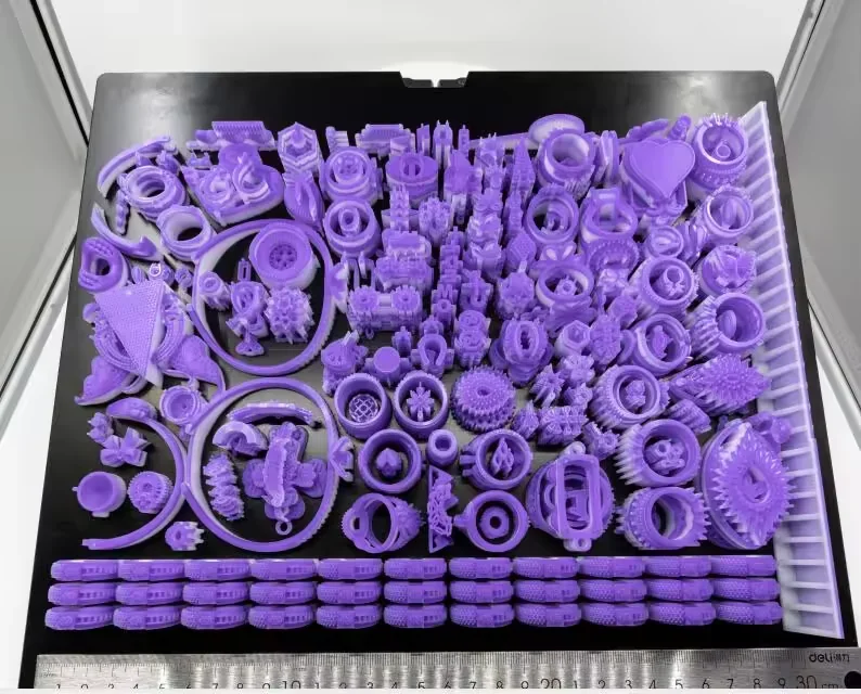 Purple 3D-printed wax parts created by Flashforge WaxJet 400 on a black surface, showcasing intricate designs and varying shapes.