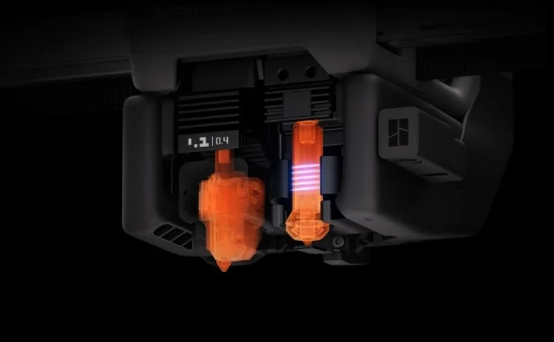 Bambu H2C 3D printer detail, showcasing advanced nozzle assembly with visible heating elements and components illuminated in orange.