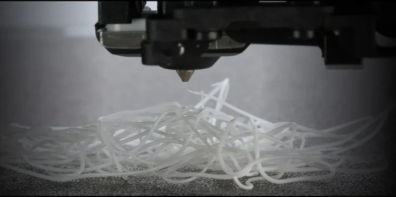 3D printer head from h2c Bambu creating intricate white filament patterns on a textured surface.