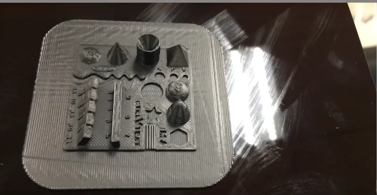 3D printed geometric shapes in dark material created by intamsys funmat ht, placed on a reflective surface, showcasing precision and detail.