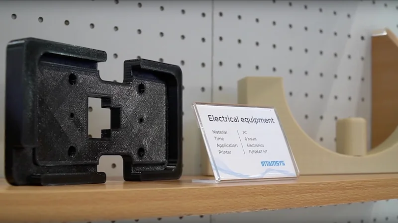 Intamsys Funmat HT-printed electrical equipment parts displayed on a wooden shelf with a descriptive label and brand logo.