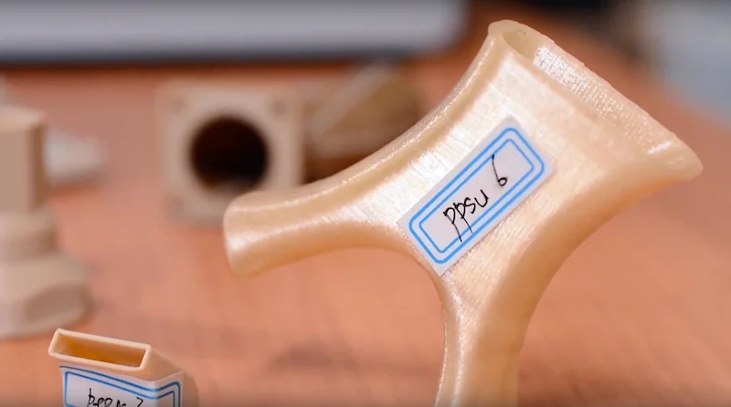 3D printed parts created by Intamsys Funmat HT, featuring detailed PPSU components on a wooden surface.