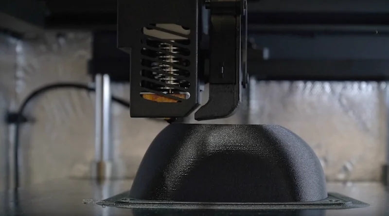 Intamsys Funmat HT printing a black part, showcasing its precision and build quality in a metallic, industrial setting.