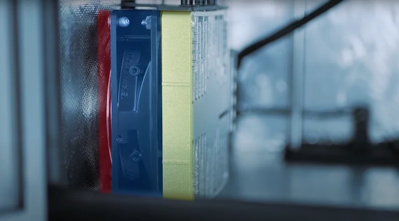 Intamsys Funmat HT printing enclosure showing partially printed blue and yellow part, enclosed by a reflective material.