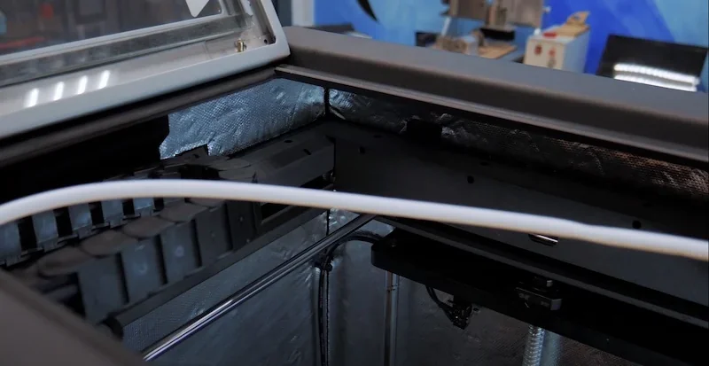 Intamsys Funmat HT internal view with filament feed and metal components, showcasing precise 3D printing technology in industrial setting.