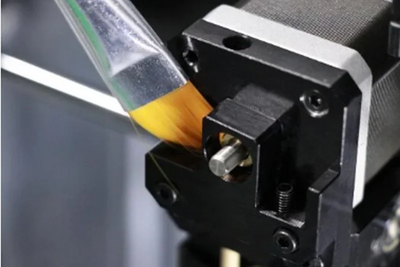 Intamsys Funmat HT printer in action with a brush cleaning mechanism, featuring close-up of extruder and filament path.