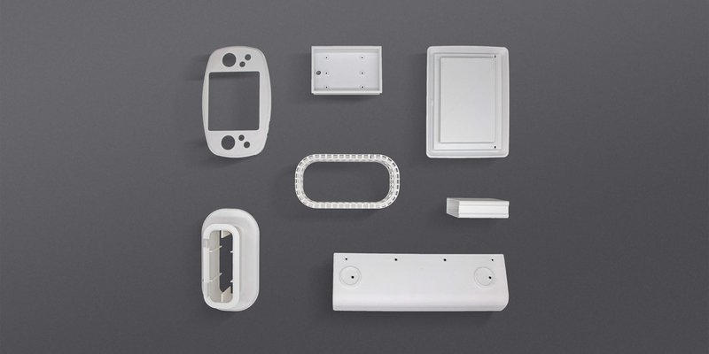 A collection of smooth, finished parts in white plastic, showcasing various shapes and structures produced by the intamsys funmat pro 310. They include rectangular, oval, and complex geometrical designs, highlighting the printer's precision and capability in manufacturing diverse components.