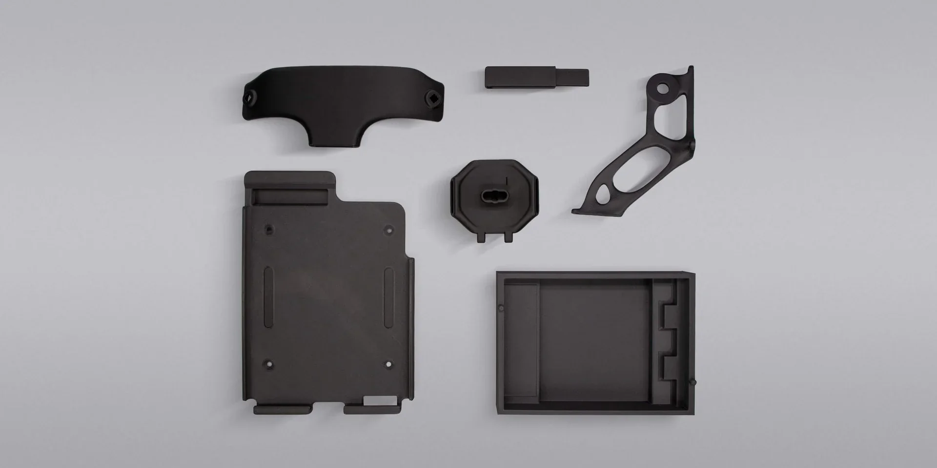 Black 3D-printed parts made by Intamsys Funmat Pro 310 displayed on a light gray background.