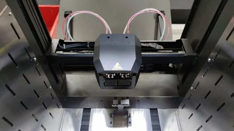 INTAMSYS Funmat Pro 410 3D printer interior showing dual extruder and build platform with visible wiring, designed for industrial-grade printing.