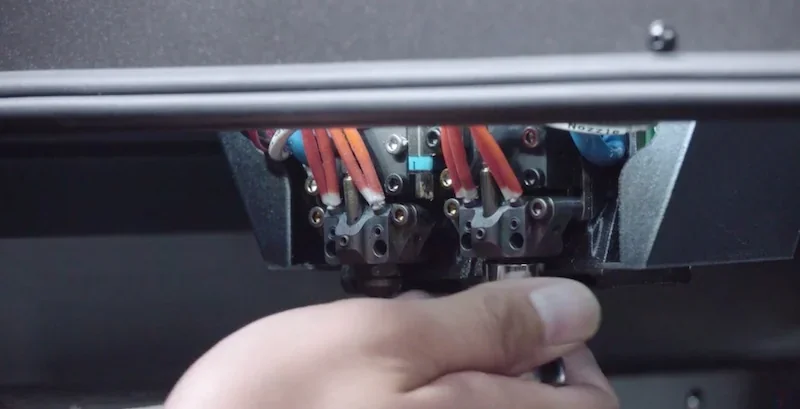 Hand adjusting intamsys funmat pro 410 3D printer extruders, showcasing detailed mechanical components likely used for precise printing tasks.