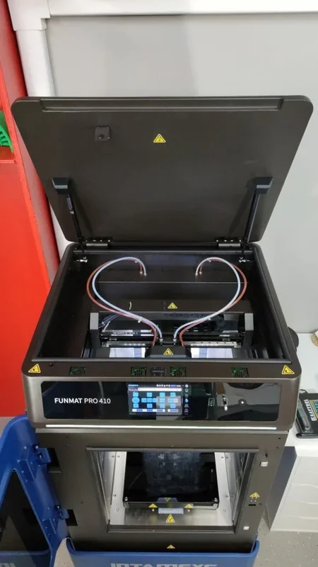Intamsys Funmat Pro 410 3D printer with open lid, control panel, dual extrusion setup. Located in a workshop setting beside other equipment.