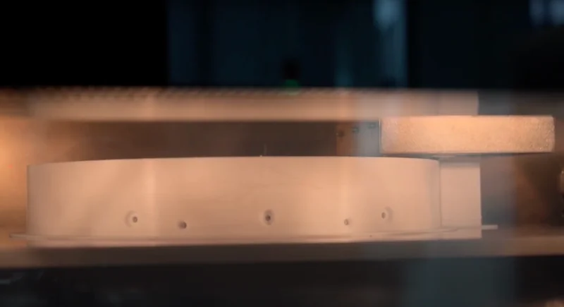 Intamsys Funmat Pro 610 HT printing a circular part inside a dimly lit chamber, showcasing advanced 3D printing capabilities.