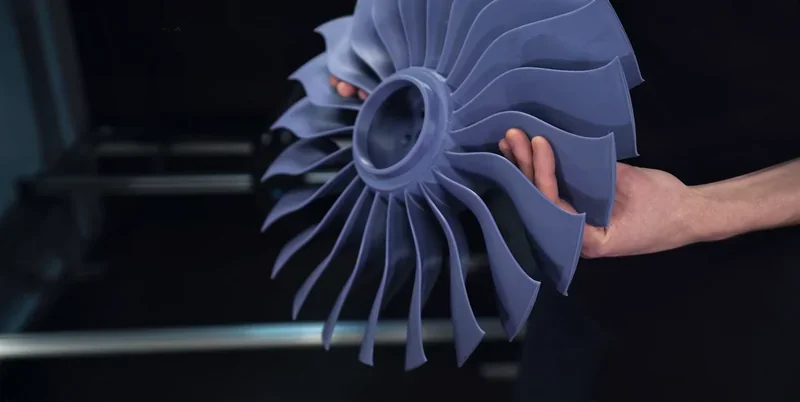 Hands holding a large, blue 3D-printed turbine part created by the Mingda MD-1000D, showcasing intricate design against a dark background.
