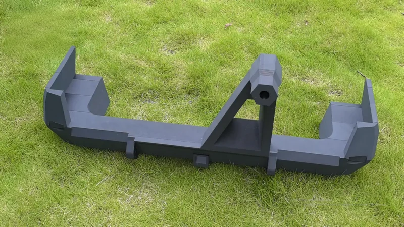 Mingda md-1000d 3D prints a large, angular black object on grass, showcasing its precision and capability in creating complex parts.