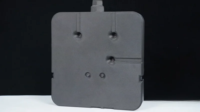 Black panel created by mingda md-1000d, featuring various circular indentations and lines, set against a dark background with white surface below.