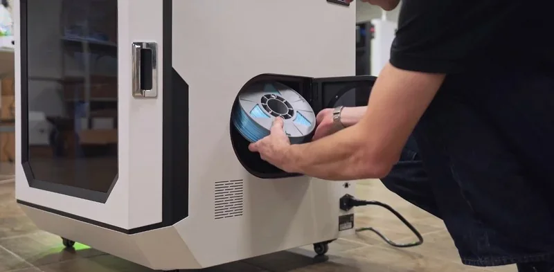 Mingda MD-400D 3D printer with a person loading a filament spool inside, set on a tiled floor in a workshop setting.