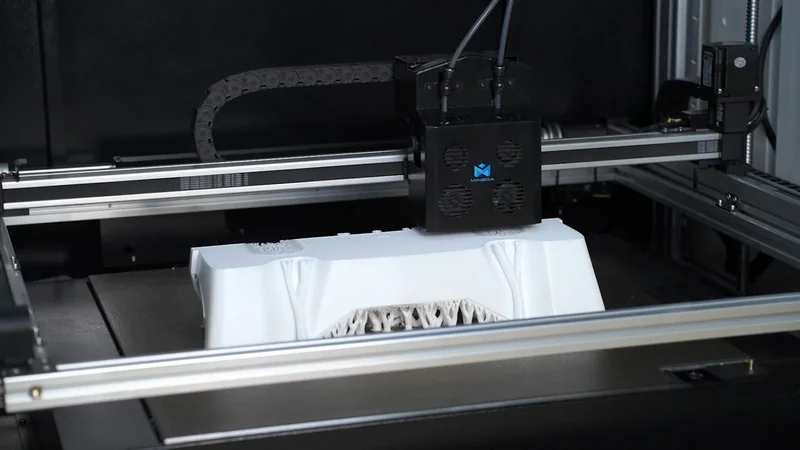 Mingda MD-600D 3D printer creating a detailed white plastic part, showcasing intricate design, set within the printer's metal and black casing.
