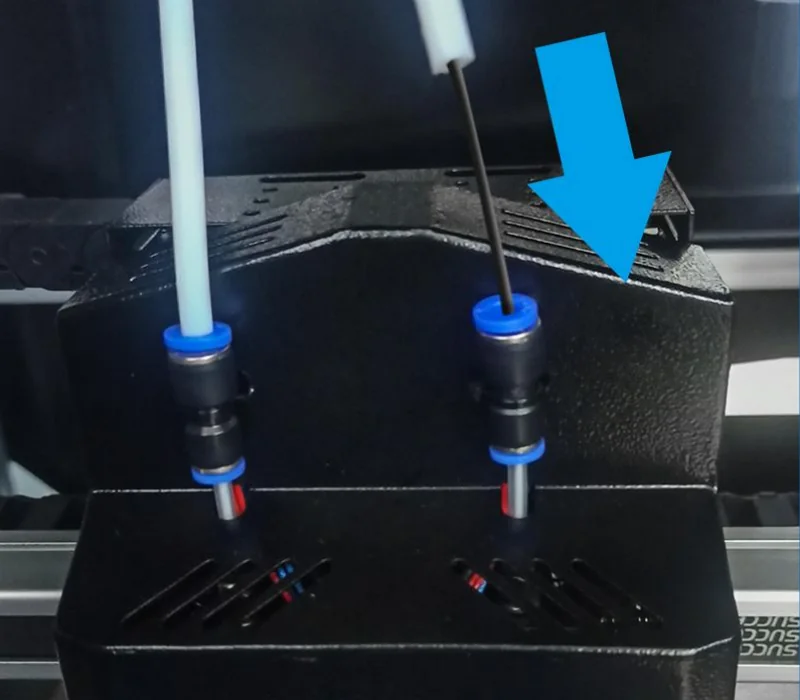 Mingda MD-600D 3D printer extruder section with two blue-capped tubes, set within a black casing, highlighted by a blue arrow.