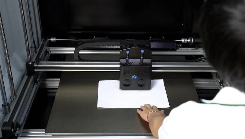 Mingda MD-600D 3D printer in operation, showing a person handling materials on the print bed, with visible printer mechanisms and branded details.