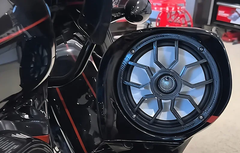 Speaker with custom grill, possibly created by the Modix Big 120x 3D printer, in a garage setting with tools visible in the background.