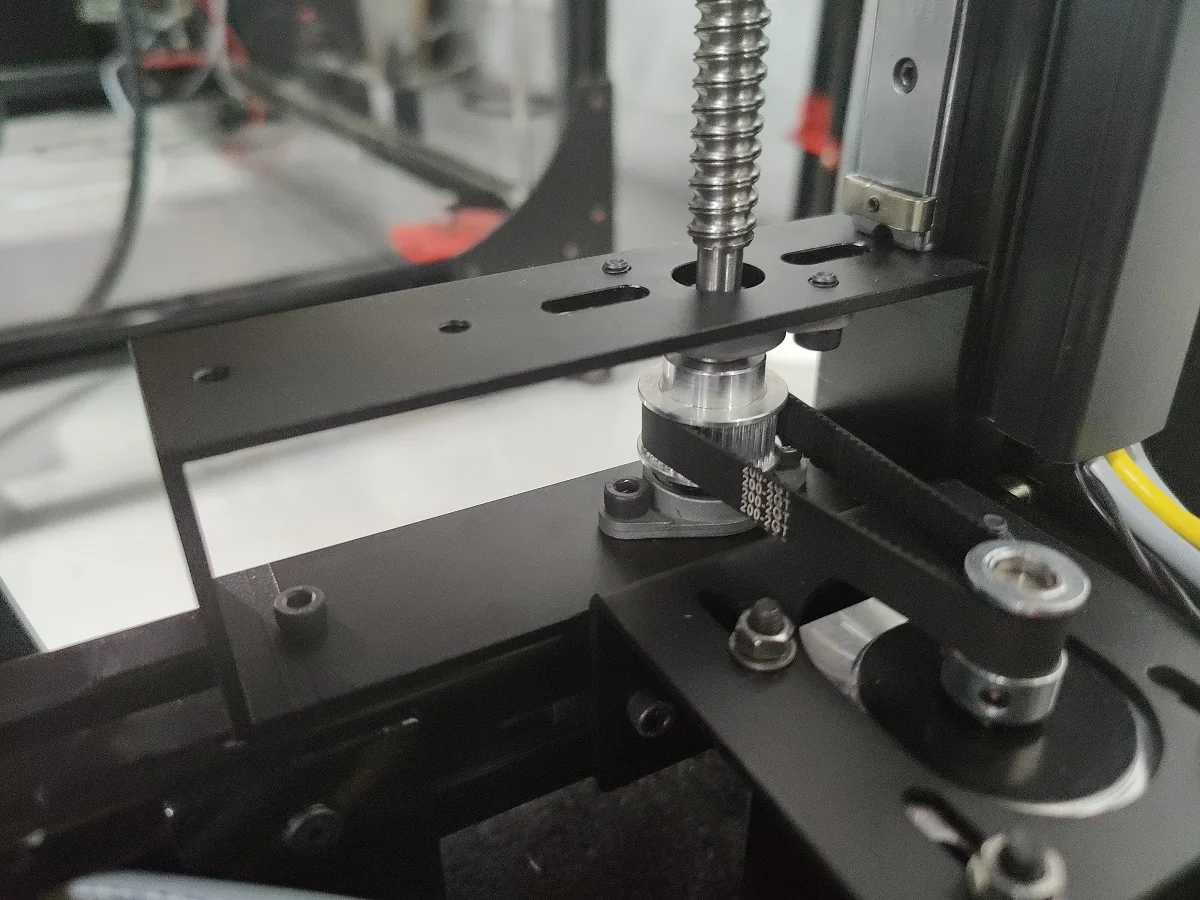 Close-up view of Modix Big 120x 3D printer component, featuring gears and belt drive system.
