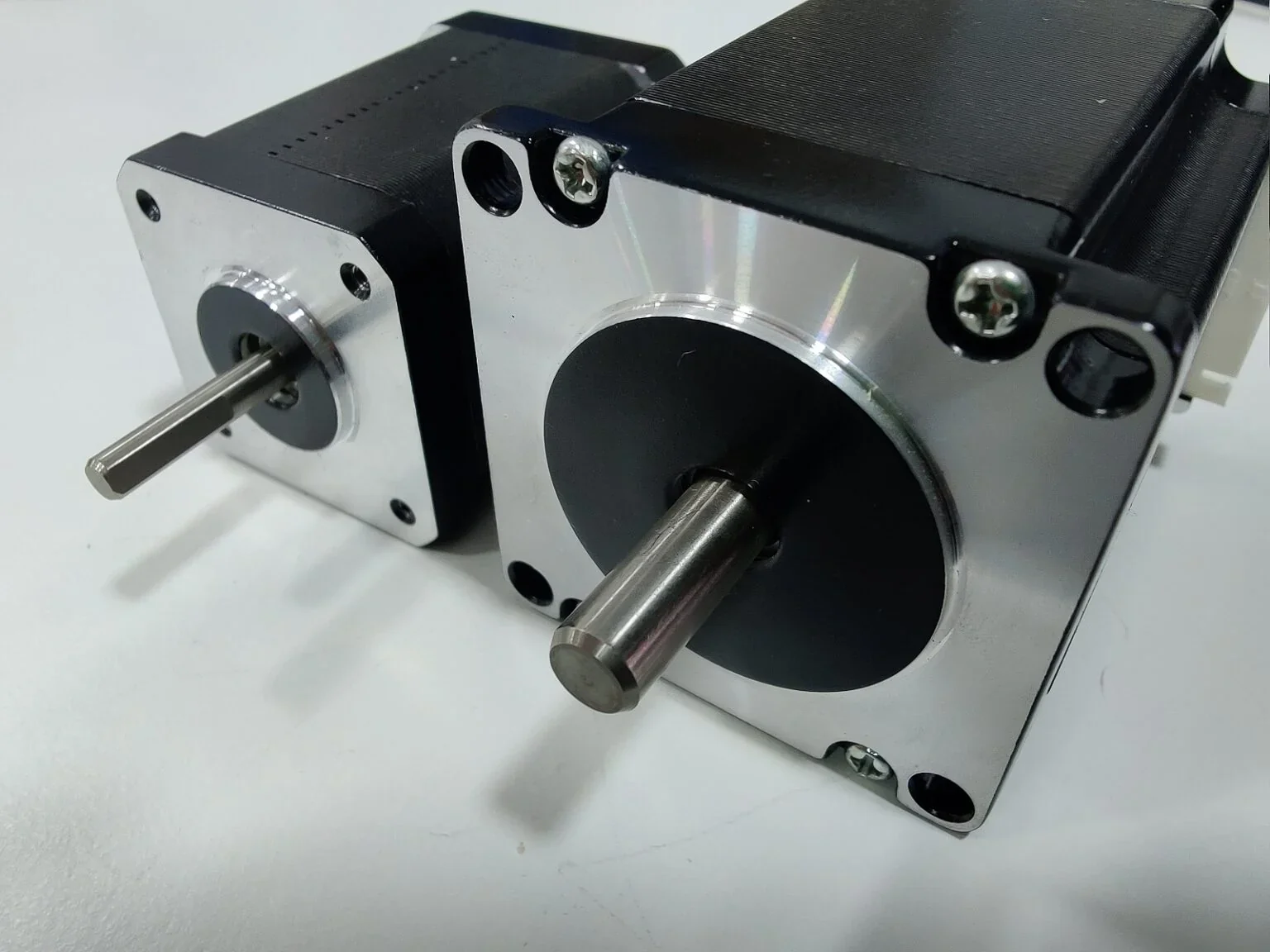 Stepper motors for Modix Big 120x 3D printer featuring metal casings and visible shafts on a white surface.