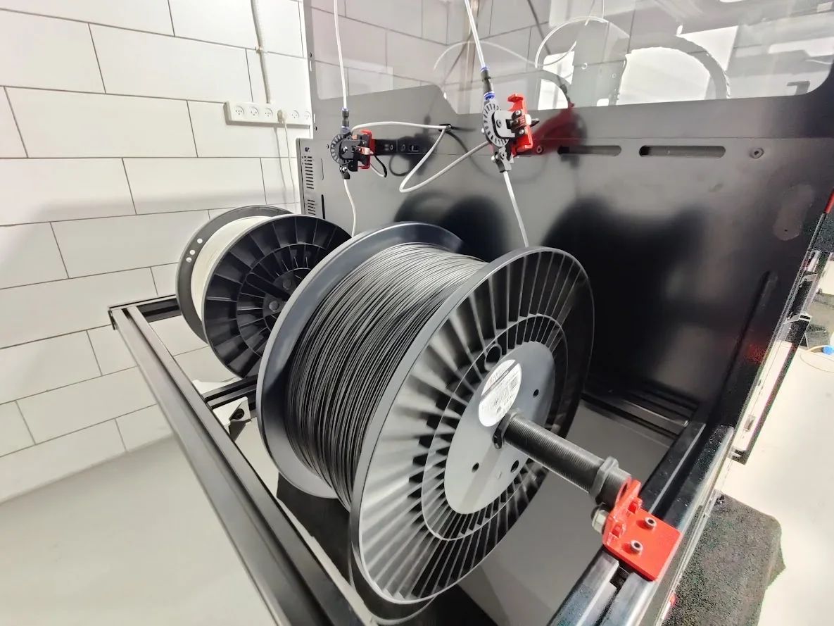 Modix Big 120X 3D printer in a tiled room with spools of filaments attached, showcasing its capabilities.