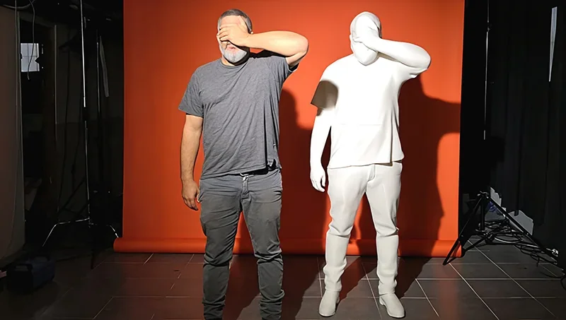 Man poses next to a white 3D-printed statue of himself against an orange backdrop, showcasing Modix Big 120Z's printing capabilities.