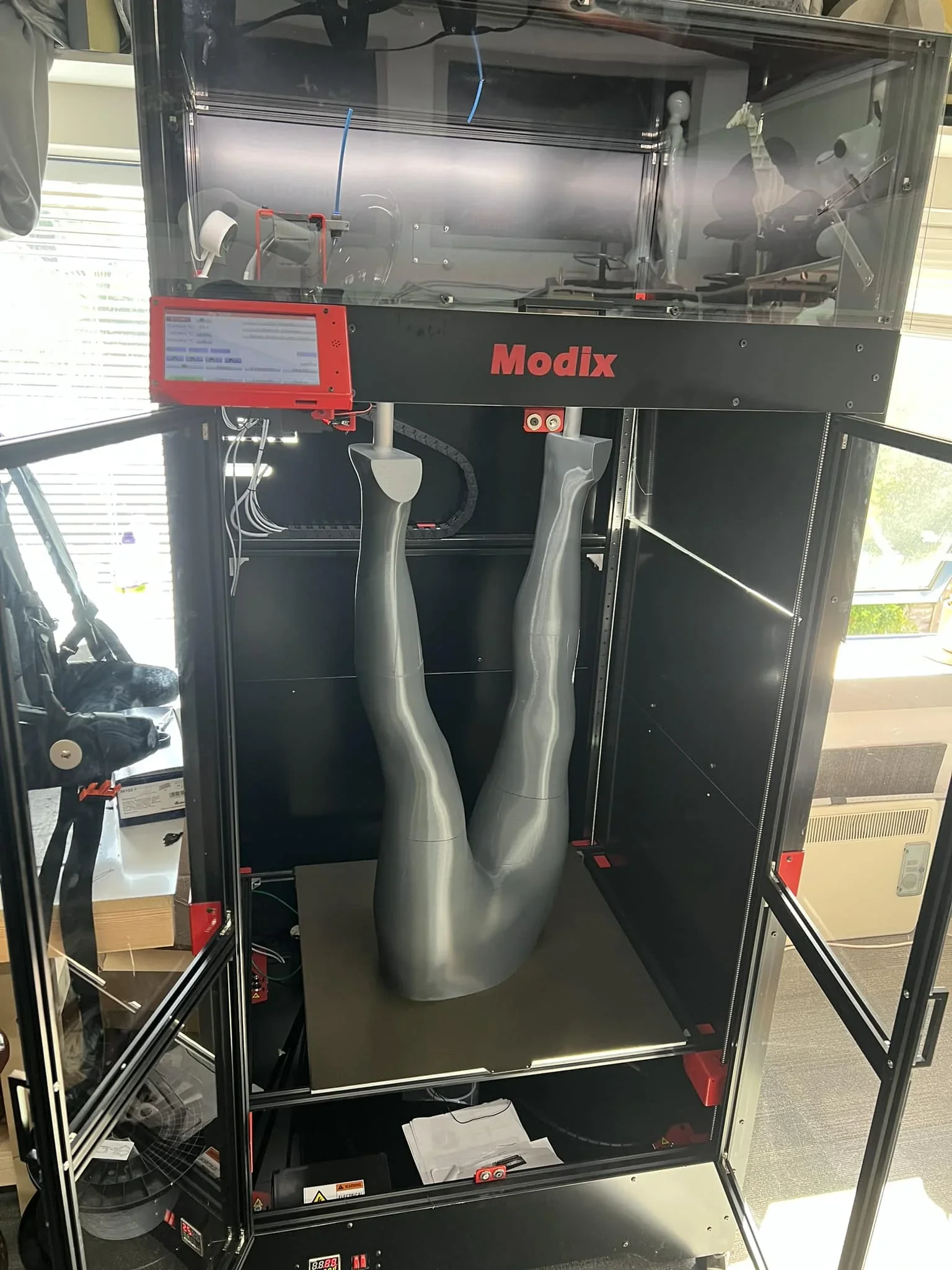 Modix Big 120Z 3D printer with a large grey leg model inside, showcasing its spacious build volume and advanced printing capabilities.