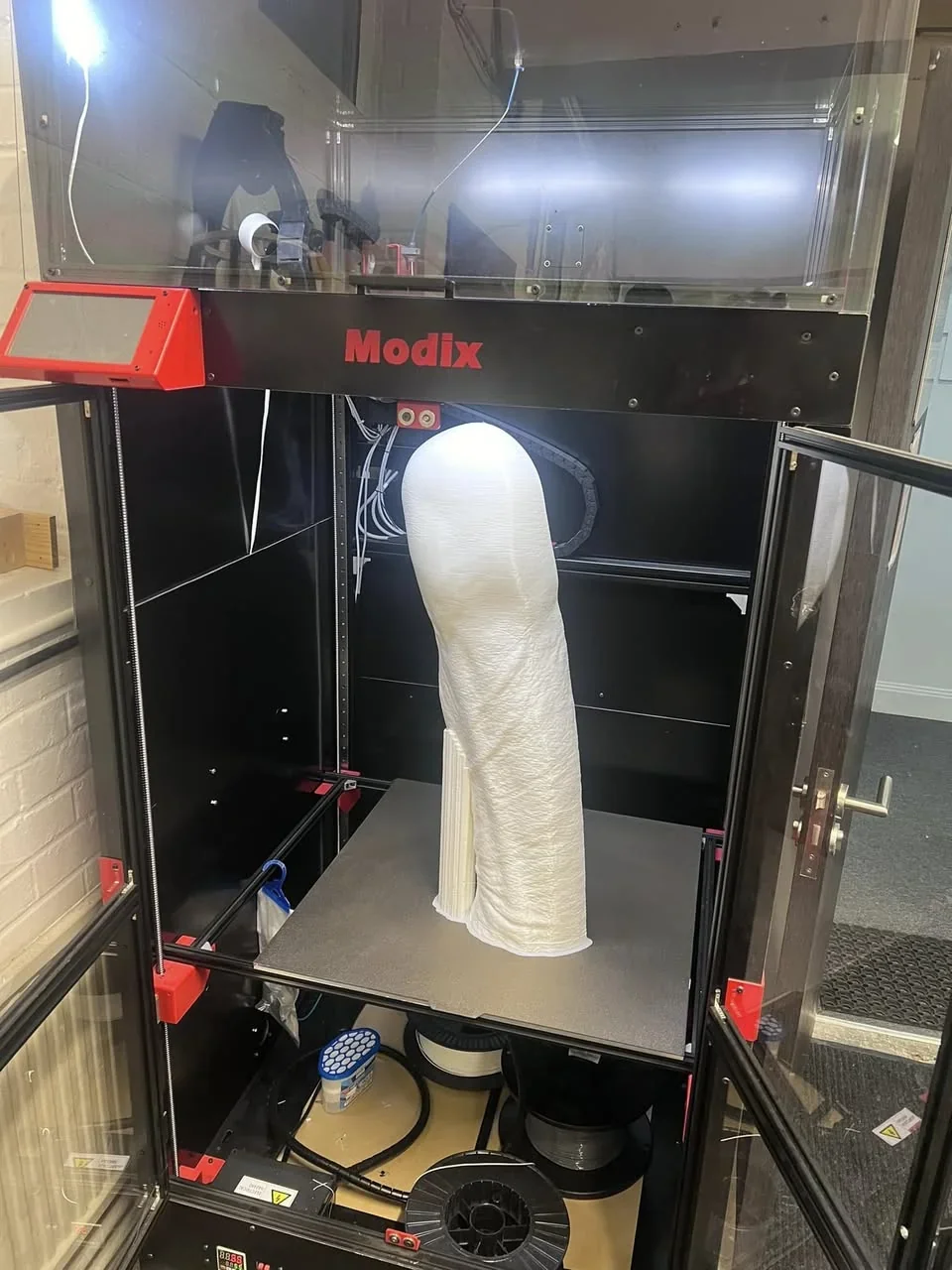 Modix Big 120Z 3D printer with a tall, intricate white print inside a transparent enclosure, featuring branding and open access doors.