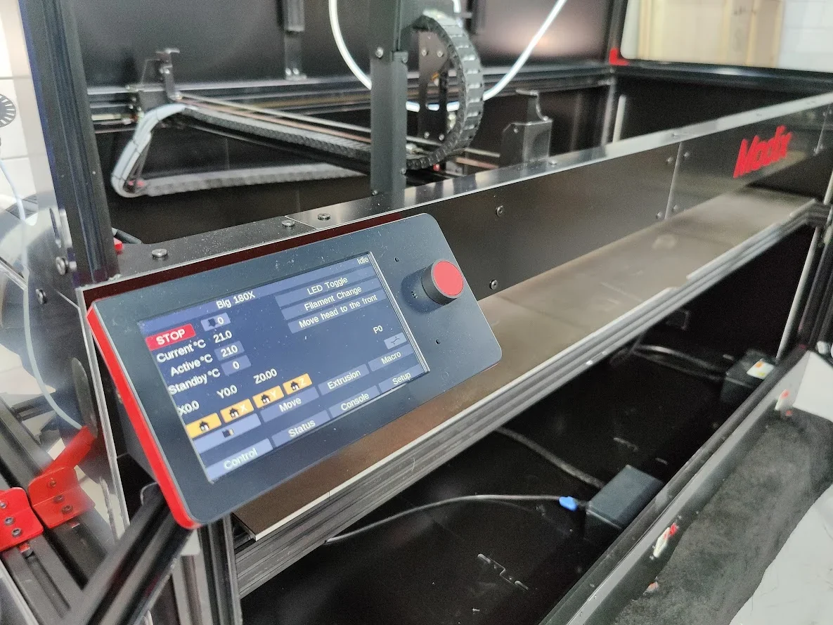 Modix Big-180X 3D printer with control panel displaying settings, within a metal frame and Modix branding visible.
