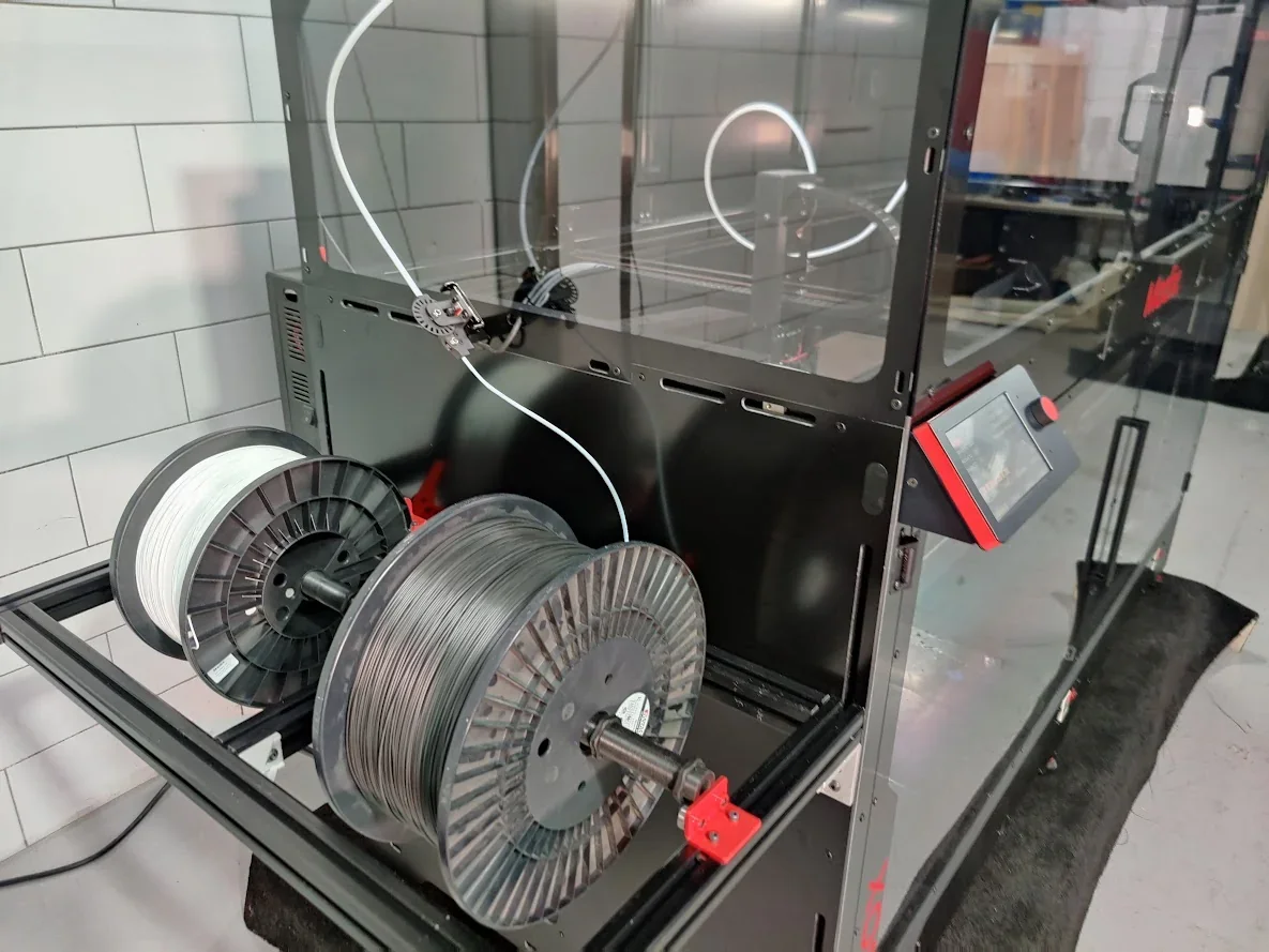 Modix Big-180x 3D printer with large filament spools, touchscreen interface, sleek enclosure, located in a workshop setting.