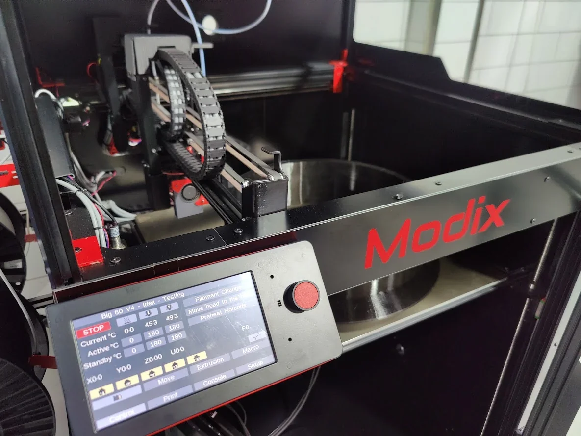 Modix Big 60 3D printer with touchscreen, visible components, and brand logo, showcasing its operational features in an industrial setting.