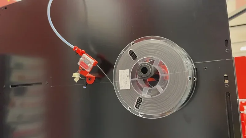 Modix Big 60 3D printer spool holder with filament roll on a sleek black casing, showcasing technical precision and efficient design features.