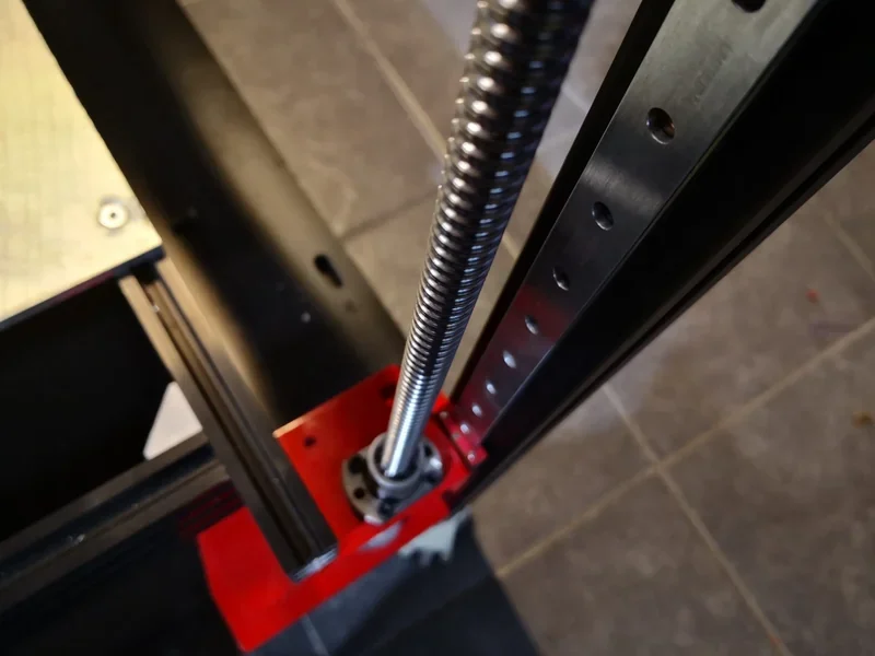 Close-up of Modix Big 60 3D printer's threaded Z-axis rod and linear rail, highlighting precise mechanics and robust construction.