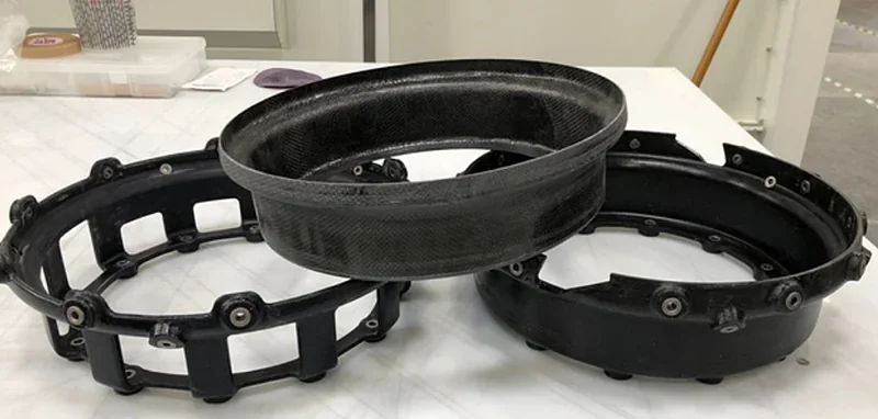 Black circular parts created by Modix Big 60 3D printer on a white surface in an industrial setting, showcasing precision and detail.