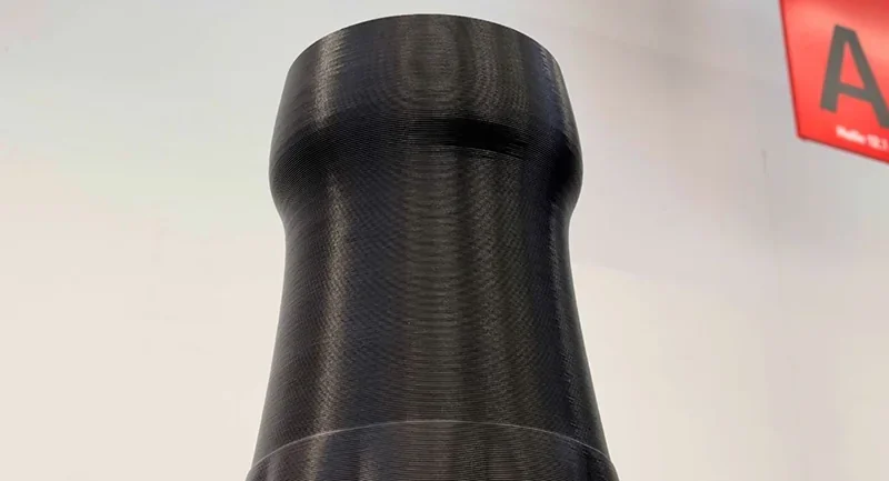 Modix Everest black 3D printed cylindrical object with detailed layers, showcasing precision and smooth finish against a light background.