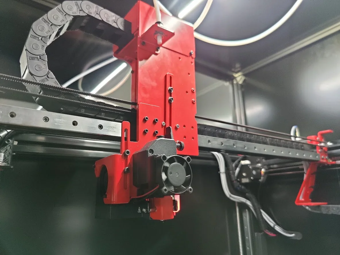 Modix Everest 3D printer close-up shows red gantry system and cables, highlighting precision engineering and component assembly.