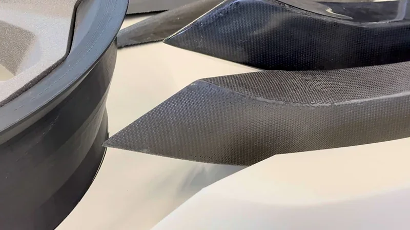 Close-up of carbon fiber parts created by Modix Everest 3D printer, showcasing sharp edges and intricate detailing on a smooth surface.
