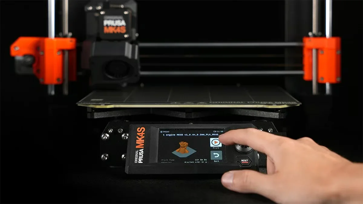 Original Prusa MK4S 3D printer kit with a touchscreen interface, hand operating controls, and printer components in a black and orange design.