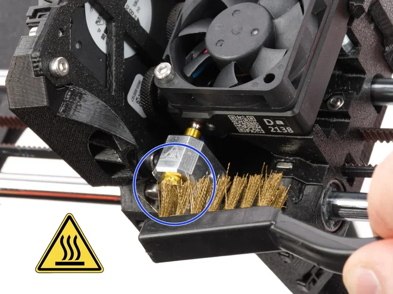 Hotend cleaning process on Original Prusa MK4S 3D Printer Kit, showing detailed nozzle maintenance with a brush and fan components.