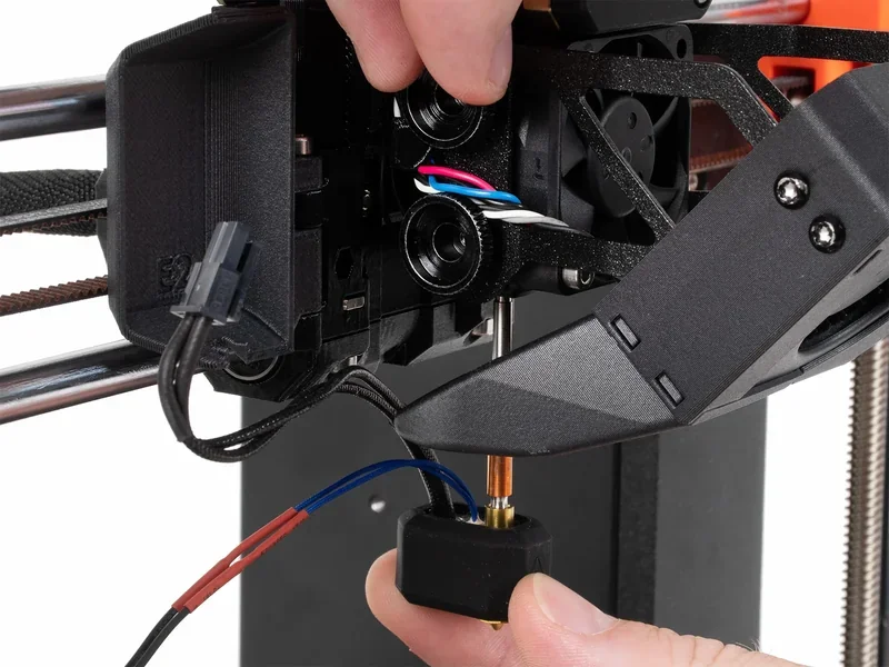 Hand adjusting nozzle assembly on Original Prusa MK4S 3D Printer Kit; visible wiring and components in focus.